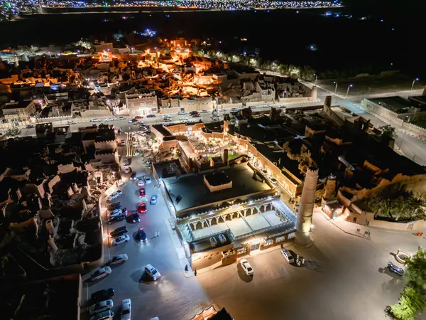 Shaqra 'nın hava gece drone görüntüsü aydınlatılmış şehir manzaraları, tarihi Najdi mimarisi ve önemli kültürel simgeler.