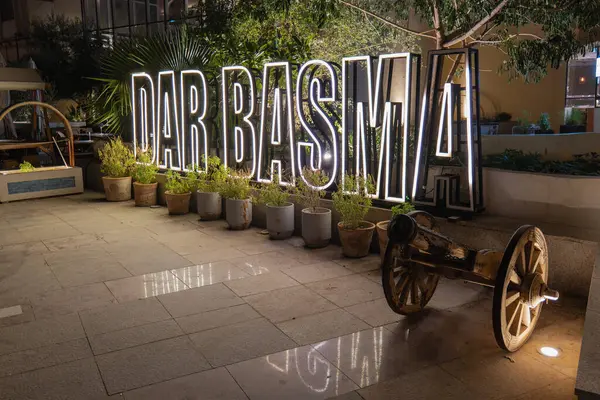 Aydınlatılmış Dar Basma restoranı tabelası gece parlıyor, tarihi Al Hofuf 'un kalbindeki miras cazibesi ve modern zarafetin bir karışımını vurguluyor..