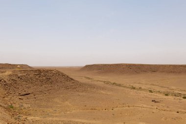 Suudi Arabistan 'ın El-Majma kenti yakınlarında çekilen bir çöl fotoğrafı Orta Arap manzarasının dingin güzelliğini yansıtıyor. Gökyüzü engin ve berrak, çölün genişliğini vurguluyor..