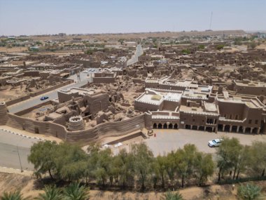 Aerial drone image of Shaqra Heritage Village showcasing preserved Najdi mudbrick homes, winding alleyways, and fortified walls, capturing the essence of Saudi heritage.