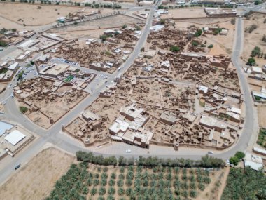 Aerial drone image of Shaqra Heritage Village showcasing preserved Najdi mudbrick homes, winding alleyways, and fortified walls, capturing the essence of Saudi heritage.
