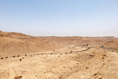 Suudi Arabistan 'ın Riyad yakınlarındaki çöl manzarası geniş ve açık arazi ve kaya oluşumlarını gösteriyor. Bu resim doğal manzaranın sessiz güzelliğini yakalar..