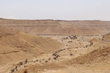 Suudi Arabistan 'ın Riyad yakınlarındaki çöl manzarası geniş ve açık arazi ve kaya oluşumlarını gösteriyor. Bu resim doğal manzaranın sessiz güzelliğini yakalar..
