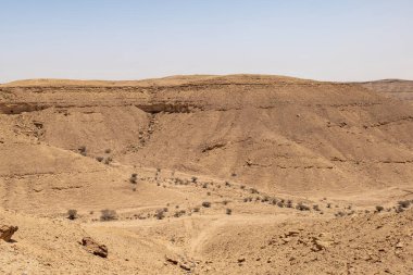 Suudi Arabistan 'ın Riyad yakınlarındaki çöl manzarası geniş ve açık arazi ve kaya oluşumlarını gösteriyor. Bu resim doğal manzaranın sessiz güzelliğini yakalar..