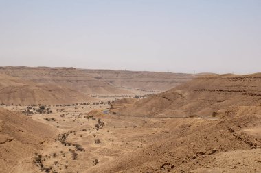 Suudi Arabistan 'ın Riyad yakınlarındaki çöl manzarası geniş ve açık arazi ve kaya oluşumlarını gösteriyor. Bu resim doğal manzaranın sessiz güzelliğini yakalar..