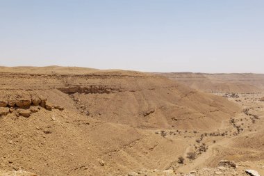Suudi Arabistan 'ın Riyad yakınlarındaki çöl manzarası geniş ve açık arazi ve kaya oluşumlarını gösteriyor. Bu resim doğal manzaranın sessiz güzelliğini yakalar..
