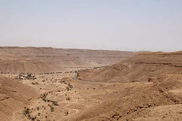 Suudi Arabistan 'ın Riyad yakınlarındaki çöl manzarası geniş ve açık arazi ve kaya oluşumlarını gösteriyor. Bu resim doğal manzaranın sessiz güzelliğini yakalar..