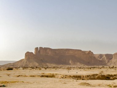 Riyad yakınlarındaki çöl manzarası, Suudi Arabistan. Yuvarlanan kum tepeleri, kayalık kayalıklar ve kuru arazi Arap Yarımadası 'nın kurak ortamının ham güzelliğini yakalıyor..