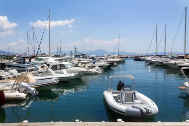 Mavi denizde yelkenli bir tekne ve İtalya 'nın Napoli Körfezi' ndeki Visuvius Dağı 'nın güzel arka planında marinada park etmiş başka bir beyaz tekne.