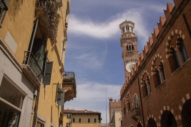 İtalya 'nın Veneto bölgesindeki Verona şehrindeki antik bir caddede, parlak mavi gökyüzü arka planına sahip İtalyan binaları ve kalesinin genel plan fotoğrafı. Verona Yazın güzel sokaklar