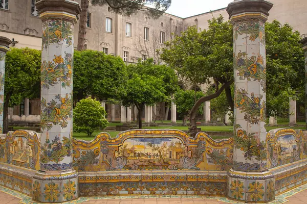 stock image Beautiful tiled pillars and the bench with fine decorations on maiolics plated at the cloister garden of Santa Chiara Monastery, Naples, Italy. Vacation in Italy