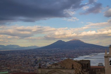 Napoli ve Napoli Körfezi 'nin güneyinde panoramik manzaralı bir şehir. Gün batımında pembe, sarı ve mavi bulutlu Vezüv volkanı. Şehir manzarası ve gökyüzü Castel Sant 'Elmo, Napoli' den.