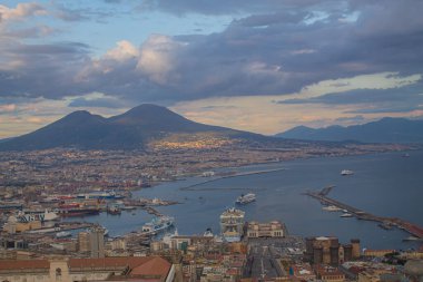 Napoli ve Napoli Körfezi 'nin güneyinde panoramik manzaralı bir şehir. Gün batımında pembe, sarı ve mavi bulutlu Vezüv volkanı. Şehir manzarası ve gökyüzü Castel Sant 'Elmo, Napoli' den.