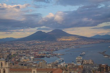 Napoli ve Napoli Körfezi 'nin güneyinde panoramik manzaralı bir şehir. Gün batımında pembe, sarı ve mavi bulutlu Vezüv volkanı. Şehir manzarası ve gökyüzü Castel Sant 'Elmo, Napoli' den.