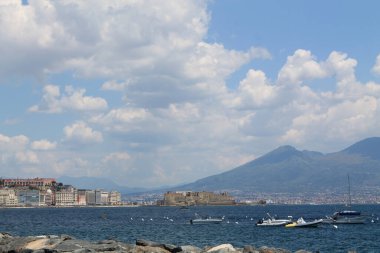 Dağların güzel arka planında mavi denizde beyaz kayıklar yüzdürmek ve İtalya 'nın Napoli Körfezi' nde Visuvius Dağı.