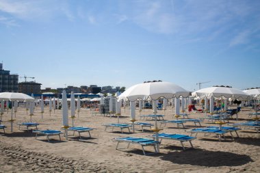 Plaj sandalyeleri ve şemsiyeler. Deniz kenarında güneşli bir günde İtalya 'da bir plajda güneşlenirler.