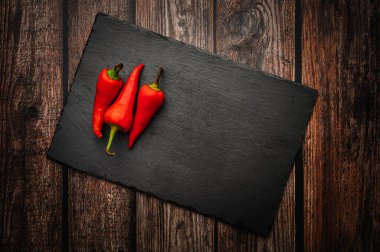 Koyu ahşap bir masada tahtada kırmızı kırmızı acı biber. Yukarıdan aşağıya genel görünüm.