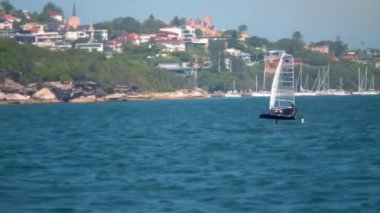 Gün batımında sakin bir denizde süzülen bir yelkenlinin yavaş çekim, sinematik çekimi. Yelkenli, uzun direği ve parlak beyaz gövdesiyle sakin sulara karşı durmaktadır. Ufuk çizgisi.