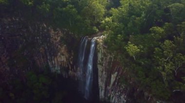 Askıya alınmış sislerin arasından eşsiz bir drone görüntüsü görkemli bir şelalenin yemyeşil yağmur ormanları dağ manzarasından aşağı aktığını gösteriyor. Bayron körfezinin yanında.
