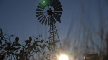 Avustralya 'nın orta kesimindeki büyük bir yel değirmeninin silueti Avustralya' nın dramatik günbatımına karşı ağır çekimde dönüyor. İnsan yok. Kırmızı merkez Uluru