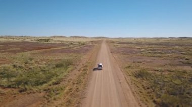 Beyaz bir minibüsün yörüngesinde dönen İHA, Avustralya 'nın batısındaki Karijini yakınlarındaki Avustralya çalılığından geçen Asutralı kırmızı toprak bir yolda ilerliyor..