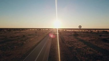 Hava görüntüsü. Avustralya 'nın orta kesimindeki büyük bir yel değirmeninin silueti Avustralya' nın dramatik günbatımına karşı ağır çekimde dönüyor. İnsan yok. Kırmızı merkez Uluru
