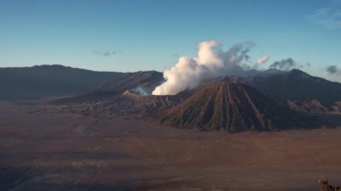 Endonezya 'daki Bromo Dağı' nın havadan görünüşü görkemli zirvesini ve volkanik manzarasını gözler önüne seriyor. Bulutlar doğanın gücünü vurgulayarak manzaraya dramatik bir dokunuş ekler.