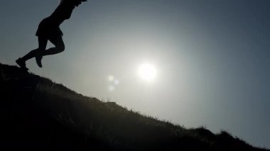 Erkek ve kadın koşucu köpeğiyle birlikte manzaralı bir tepe boyunca koşuyor. Altın sonbahar günışığının son ışınları güzel dağlık araziye yayılıyor. Resmedilmeye değer bir çayır sırtına doğru koşuyorlar.