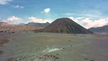 Endonezya 'daki Bromo Dağı' nın havadan görünüşü görkemli zirvesini ve volkanik manzarasını gözler önüne seriyor. Bulutlar doğanın gücünü vurgulayarak manzaraya dramatik bir dokunuş ekler.