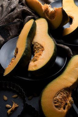 Kesilmiş balkabağı parçaları karanlık tabaklarla kaplı masada.