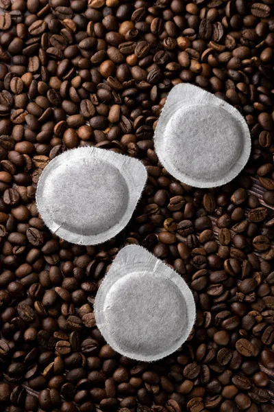 Paper pods for coffee machine on coffee beans background