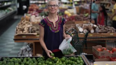 Marketten limon seçen güzel gülümseyen olgun bir kadının portresi. Etnik kıyafetler giyiyor..