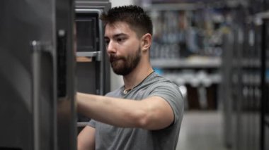 Evdeki mutfak gereçleri bölümündeki hırdavatçıda buzdolabı alışverişi yapan adama yakın çekim..