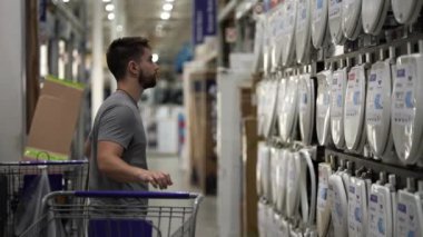 Genç adam, tuvalet aksesuarları bölümünde klozet kapağını seçerek ev geliştirme hırdavatçısından alışveriş yapıyor..