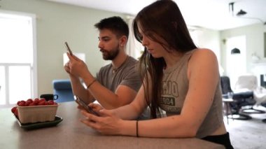 Geniş açı, evde beraberken mesajlaşan ve telefon kullanan genç çifte odaklan.