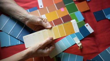 Bir kadının elleri örnek boya örneklerini karşılaştırırken ve renk karışımını düşünürken yakındır..