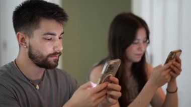 Genç mutlu çiftin telefonlarıyla kafede mesajlaşmaları, araştırmaları, daktilo etmeleri ve çalışmalarının aşırı yakınlaşması..