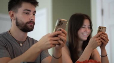 Genç mutlu çiftin telefonlarıyla kafede mesajlaşmaları, araştırmaları, daktilo etmeleri ve çalışmalarının aşırı yakınlaşması..