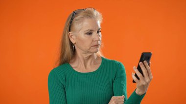 40 'lı yaşlarda olgun bir kadının turuncu arka plan stüdyosunda yalnız poz vermesine şaşırdım. İnsanların yaşam tarzı konsepti. Gözleri gören kameraya bakıyorum..