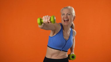 40 'lı yaşlarda olgun bir kadının turuncu arka plan stüdyosunda yalnız poz vermesine şaşırdım. İnsanların yaşam tarzı konsepti. Gözleri gören kameraya bakıyorum..