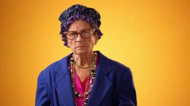 Mutlu gülümseyen çılgın büyükannenin komik portresi. 80 'li yaşlarda olgun bir kadın. Sarı arka planda izole edilmiş gibi davranıyor.