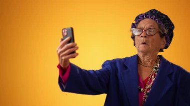 Mutlu gülümseyen çılgın büyükannenin komik portresi. 80 'li yaşlarda olgun bir kadın. Sarı arka planda izole edilmiş gibi davranıyor.