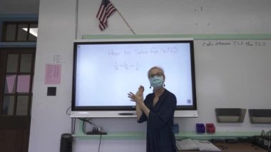 Etkileşimli bir beyaz tahtaya yazı yazan kadın öğretmenin sınıfta matematik öğrettiği yakın plan..