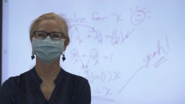 Etkileşimli bir beyaz tahtaya yazı yazan kadın öğretmenin sınıfta matematik öğrettiği yakın plan..