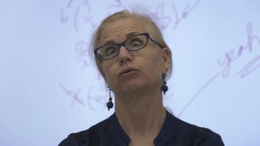 Etkileşimli bir beyaz tahtaya yazı yazan kadın öğretmenin sınıfta matematik öğrettiği yakın plan..