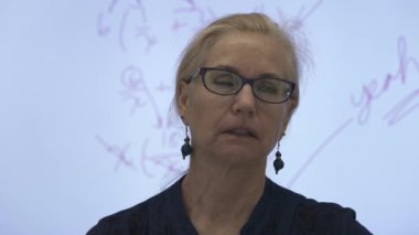 Etkileşimli bir beyaz tahtaya yazı yazan kadın öğretmenin sınıfta matematik öğrettiği yakın plan..