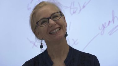 Etkileşimli bir beyaz tahtaya yazı yazan kadın öğretmenin sınıfta matematik öğrettiği yakın plan..