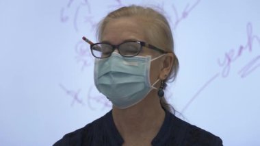 Etkileşimli bir beyaz tahtaya yazı yazan kadın öğretmenin sınıfta matematik öğrettiği yakın plan..