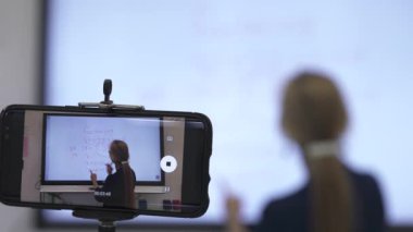 Etkileşimli bir beyaz tahtaya yazı yazan kadın öğretmenin sınıfta matematik öğrettiği yakın plan..