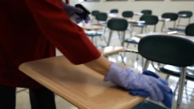 Sprey şişe, eldiven, bez, silme, temizlik ve okul sıralarını dezenfekte eden kadın öğretmenlerin el resimleri..